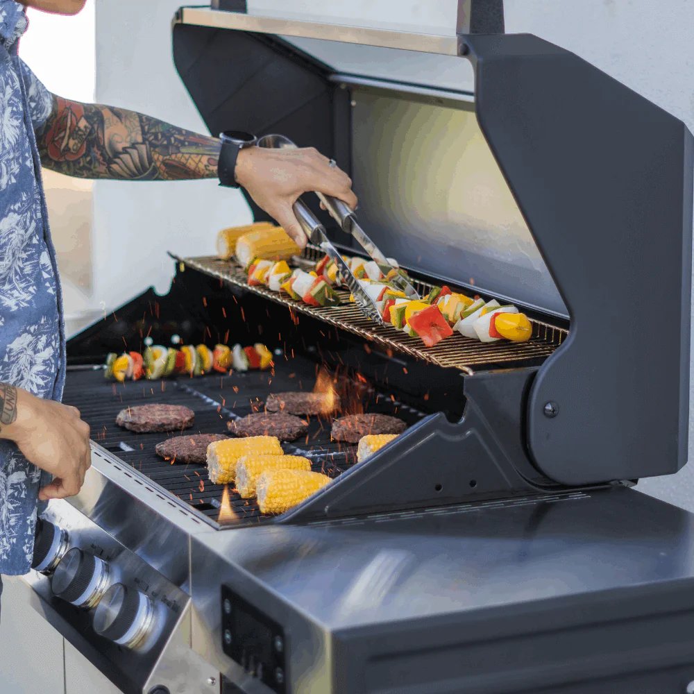 Person grilling vegetables and meats on a Monument Grills Denali 405