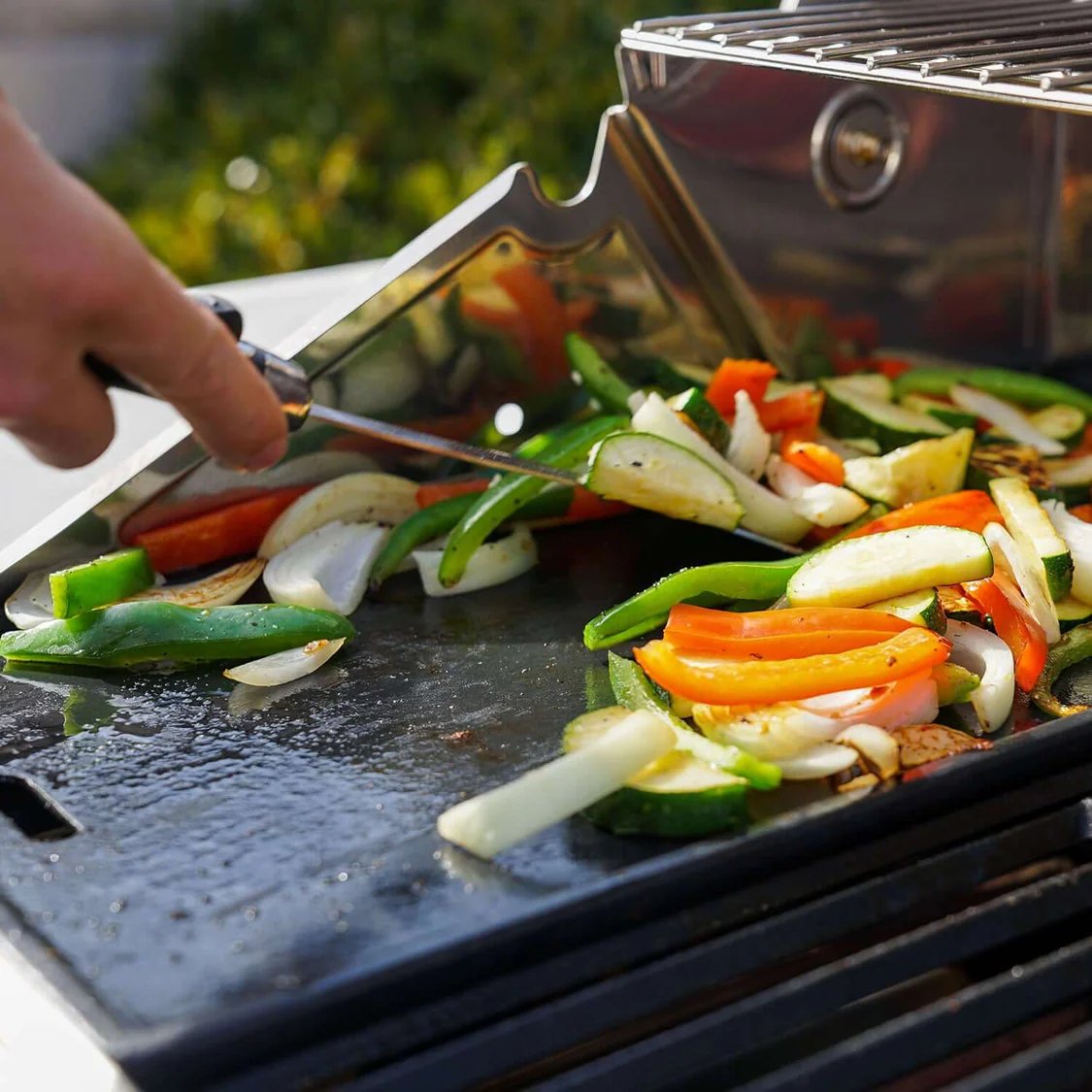 Person grilling vegetables on a Monument Grills Denali 605 Pro
