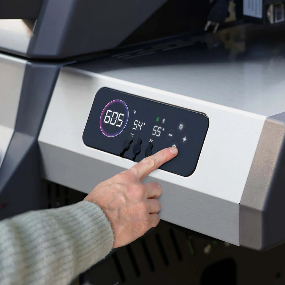 Hand adjusting settings on a digital control panel of Monument Grills Eminence 605