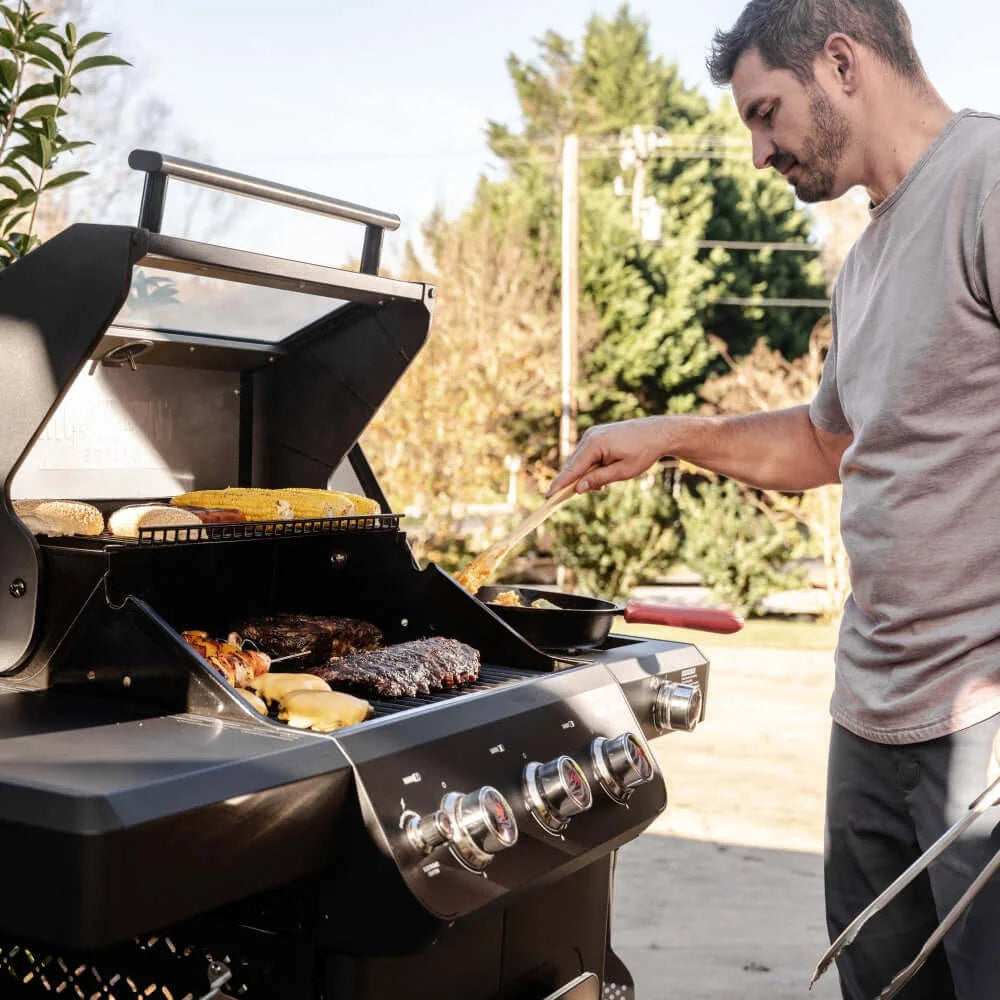 A man grilling outdoors using a Monument Grills Mesa 325