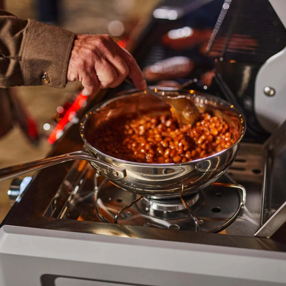 A person stirs a pot of beans on the Monument Grills Mesa 415BZ stove.