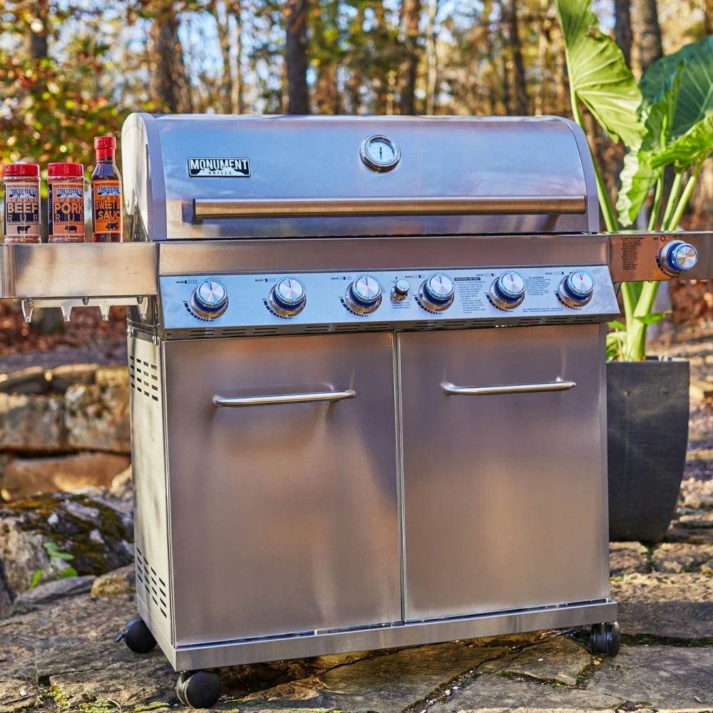 Stainless steel grill with seasoning bottles on a natural outdoor setting