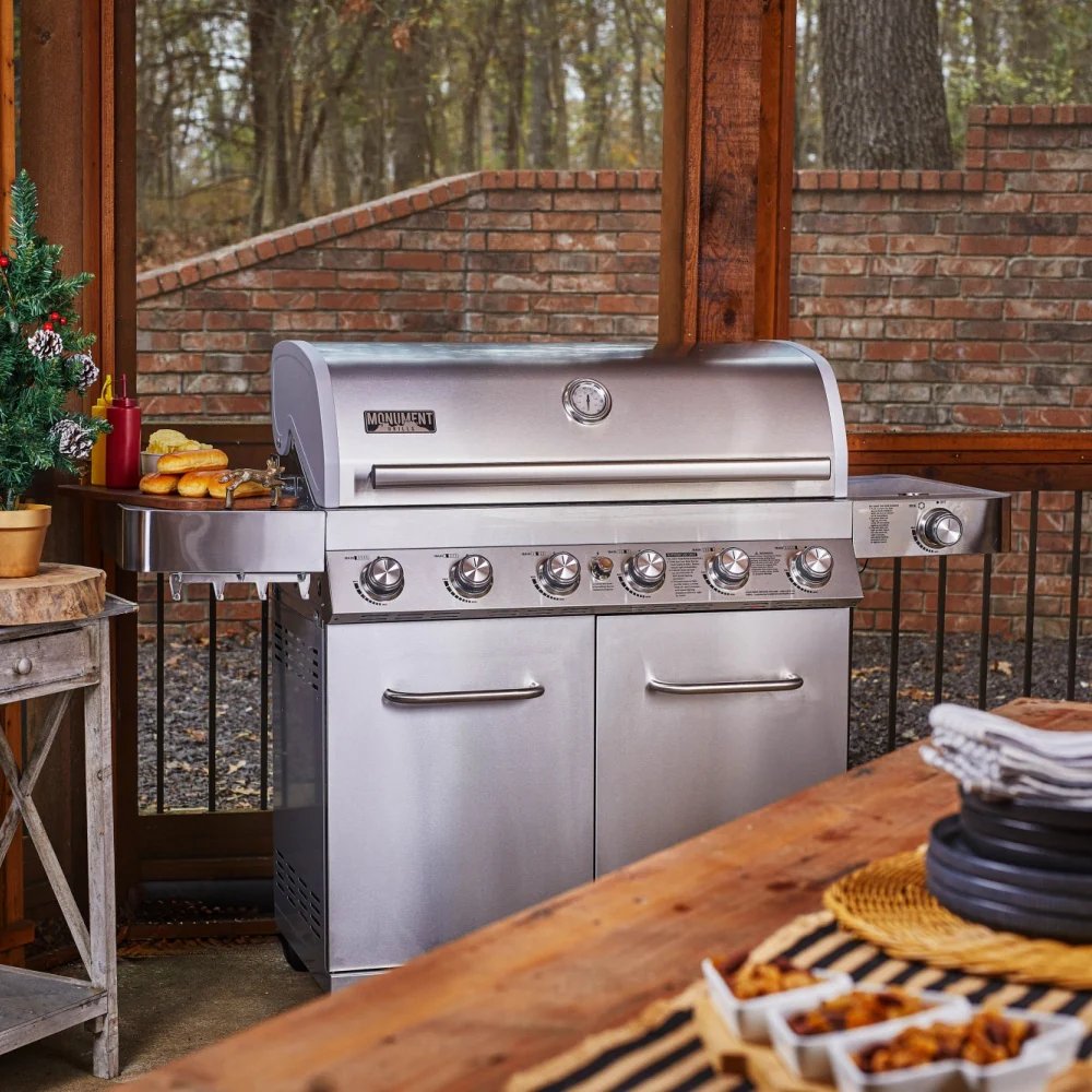 Stainless steel grill on an outdoor patio with a wooden table and decorative items.