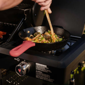 Person stirring food in a frying pan on a portable stove of Monument Grills Mesa 325