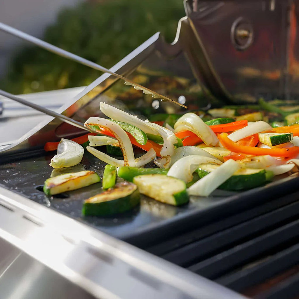 Vegetables being grilled on a barbecue with tongs