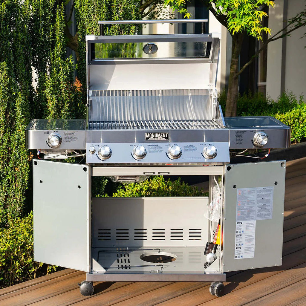 Stainless steel grill on a wooden deck with greenery in the background