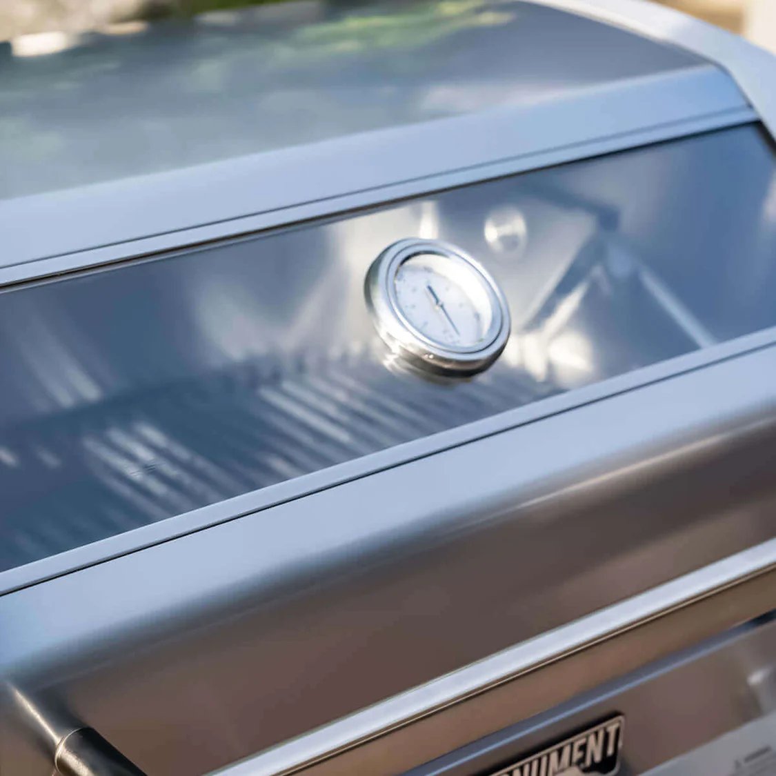 Close-up of a grill with a thermometer on a blurred outdoor background