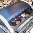 Grill with burgers cooking on a stone patio