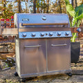Stainless steel grill with seasoning bottles on a natural outdoor setting