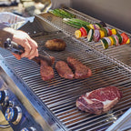 Person grilling meat and vegetables on a barbecue