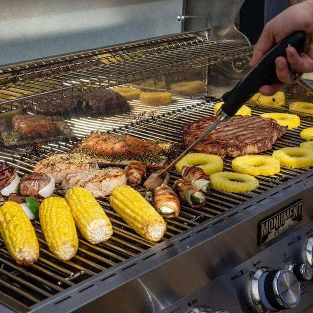 Grilling scene with various meats and vegetables on a barbecue, including corn and pineapple rings.