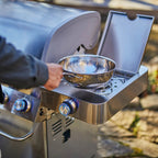 Person using a portable stove with a pan outdoors