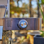 Control panel of a grill with a blurred outdoor background