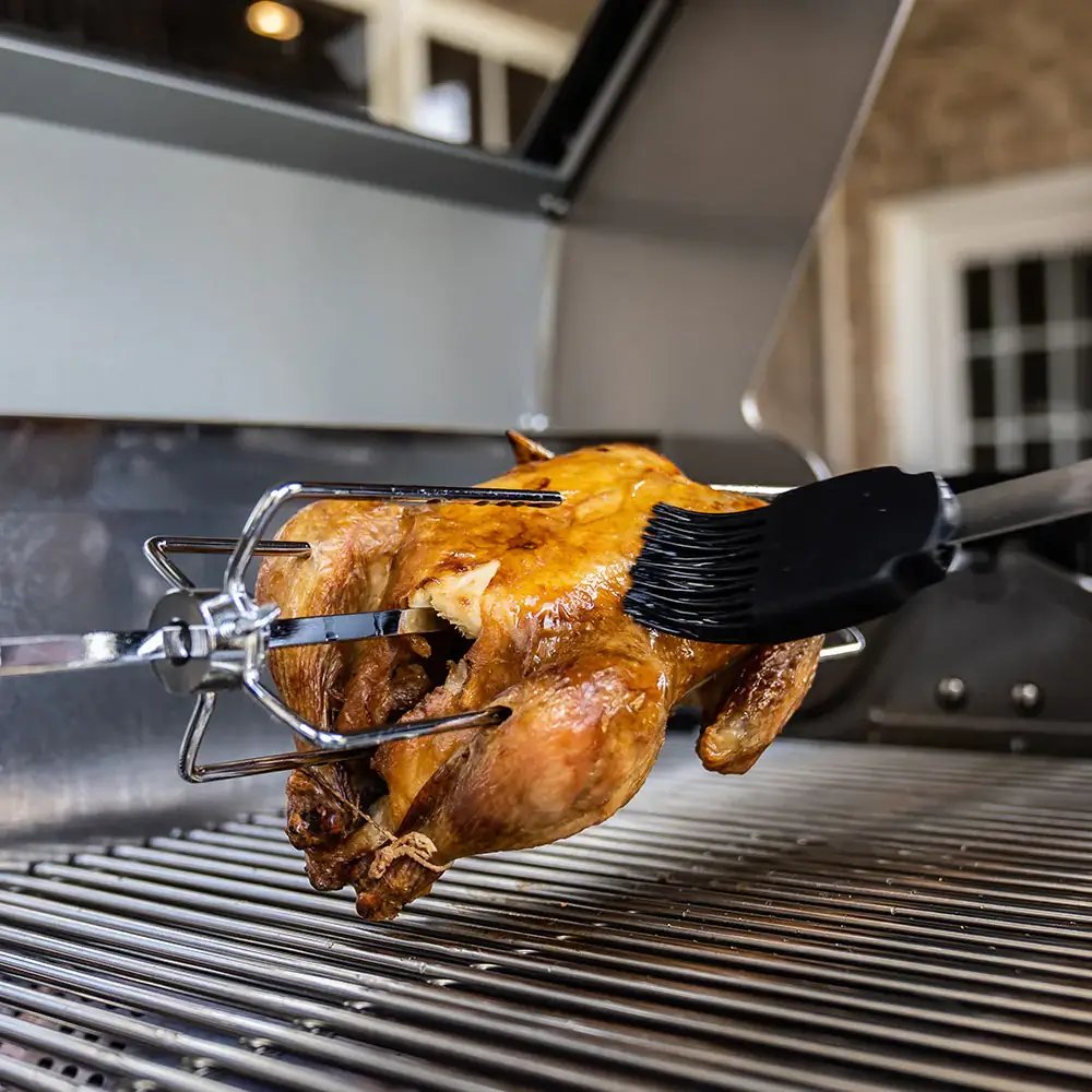 Roasted chicken on a rotisserie over a grill