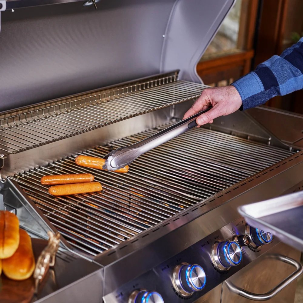 Person grilling hot dogs on a stainless steel barbecue grill.