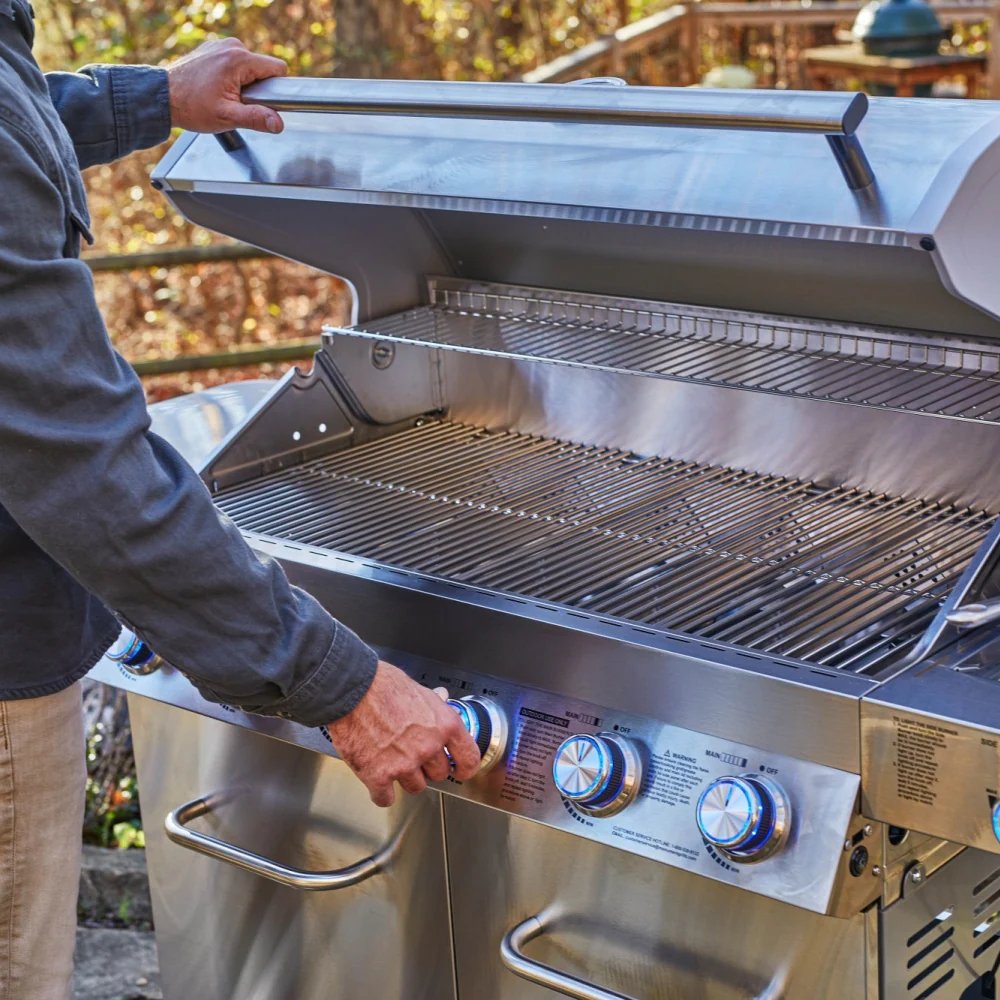 Person opening a stainless steel grill outdoors