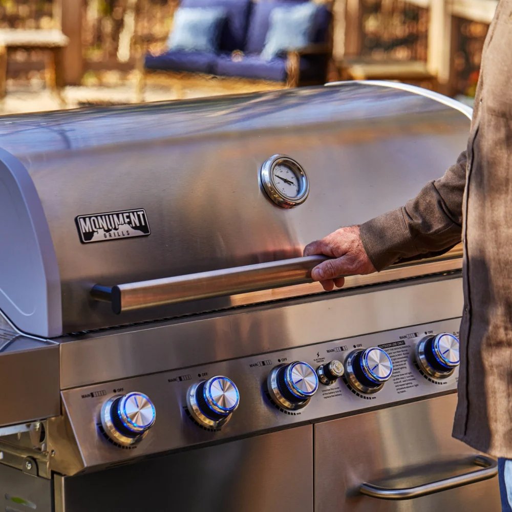 Stainless steel grill with a person opening the lid outdoors