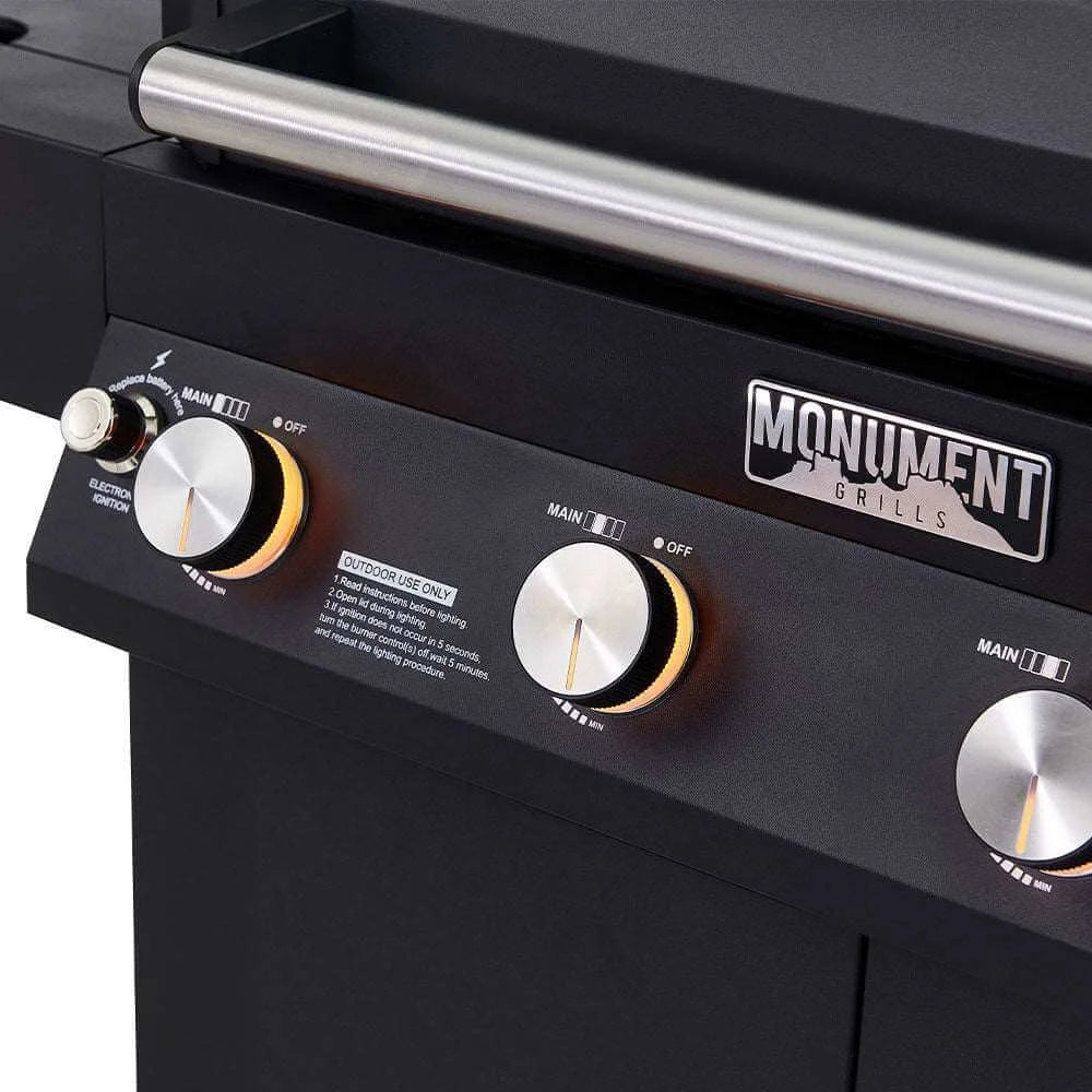 Close-up of a black grill with control knobs and 'Monument Grills' branding.