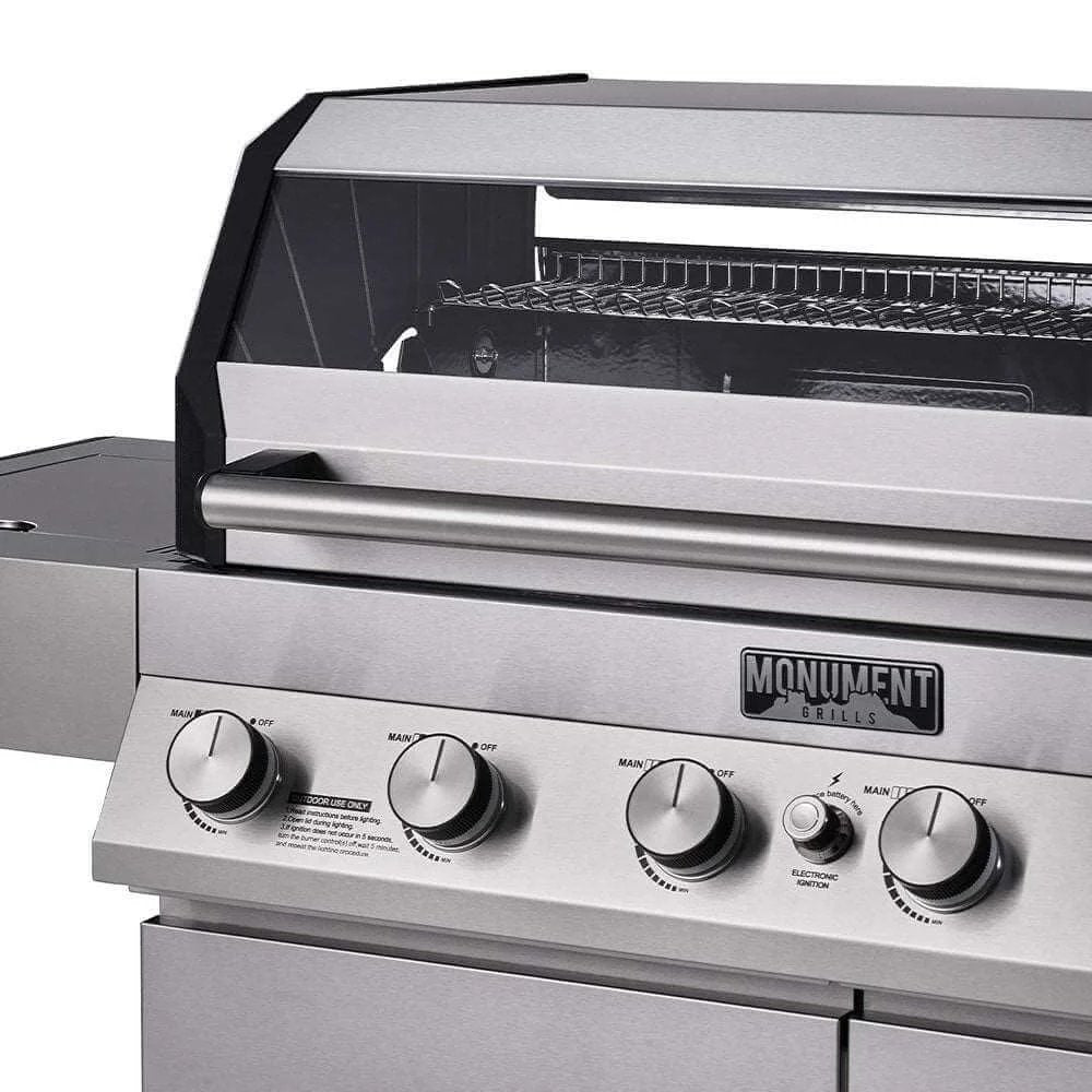Close-up of a stainless steel grill with control knobs and 'Monument Grills' branding.