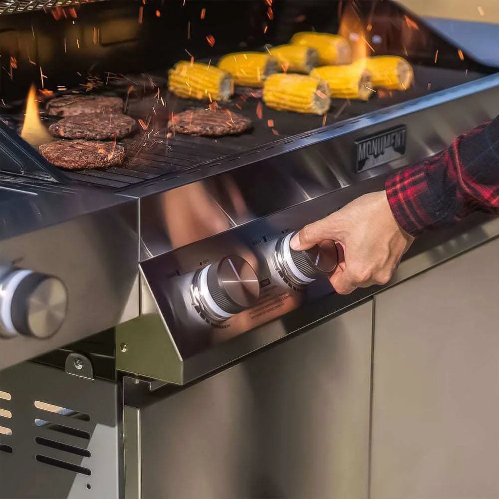Person adjusting knobs on a grill with burgers and corn cooking.