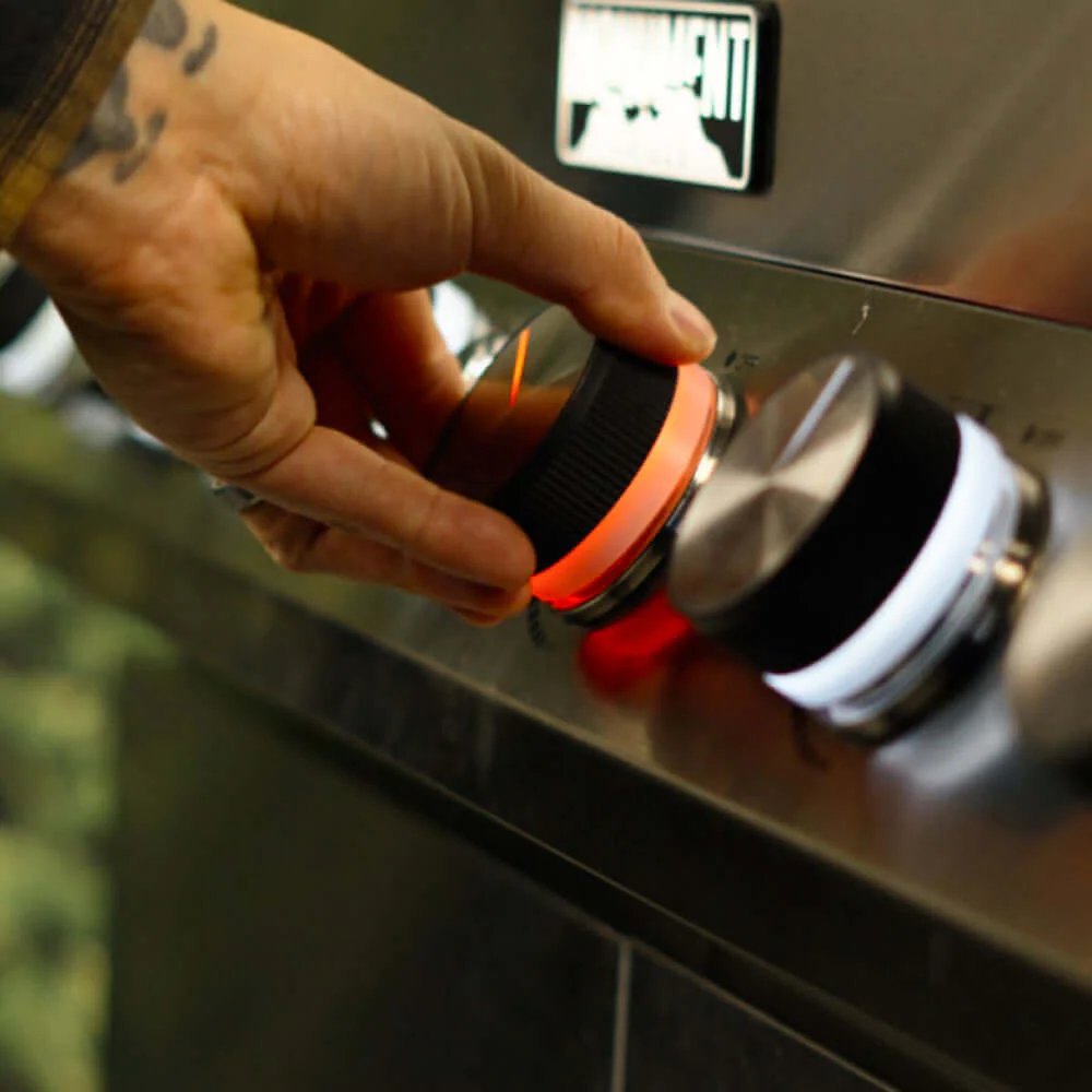Hand adjusting a gas stove knob on a stovetop