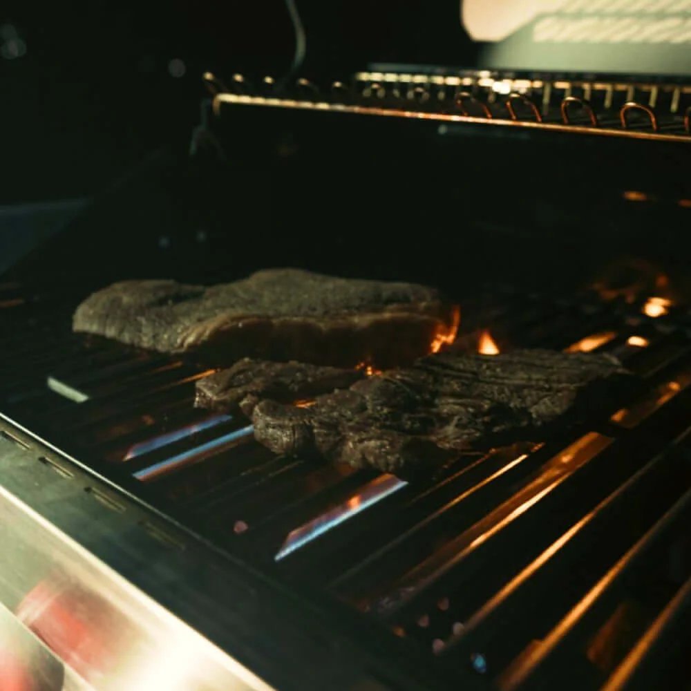 Meat cooking on a grill with flames visible