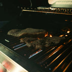 Meat cooking on a grill with flames visible
