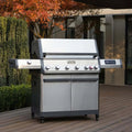 Stainless steel grill on a wooden deck with trees and a building in the background