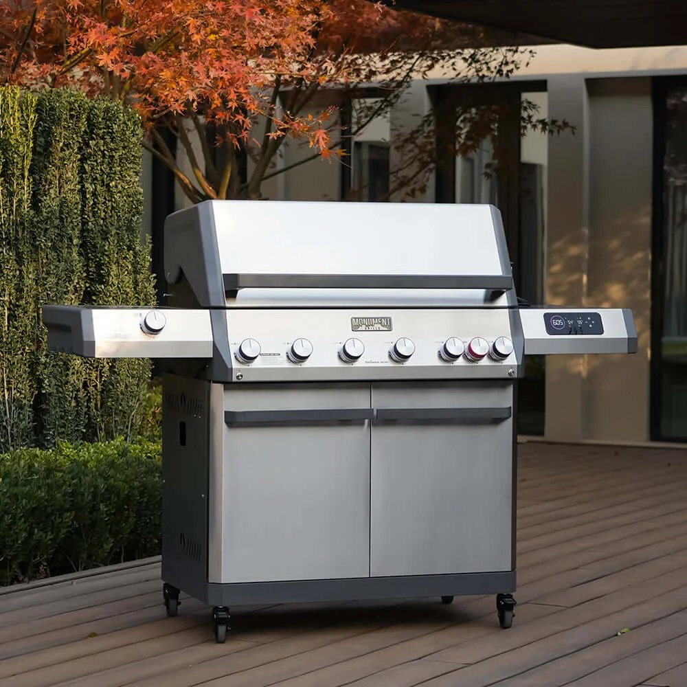 Stainless steel grill on a wooden deck with trees and a building in the background