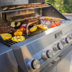 Barbecue grill with various foods being cooked outdoors