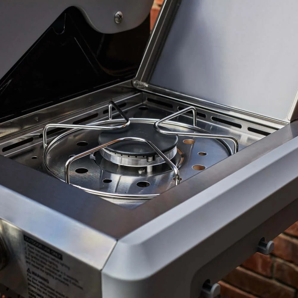 Close-up of a portable gas stove with a brick wall in the background