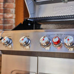 Close-up of a stainless steel grill with control knobs on an outdoor setting.