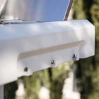 Close-up of a white outdoor grill with trees in the background