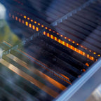 Close-up of a grill with glowing coals and metal grates.