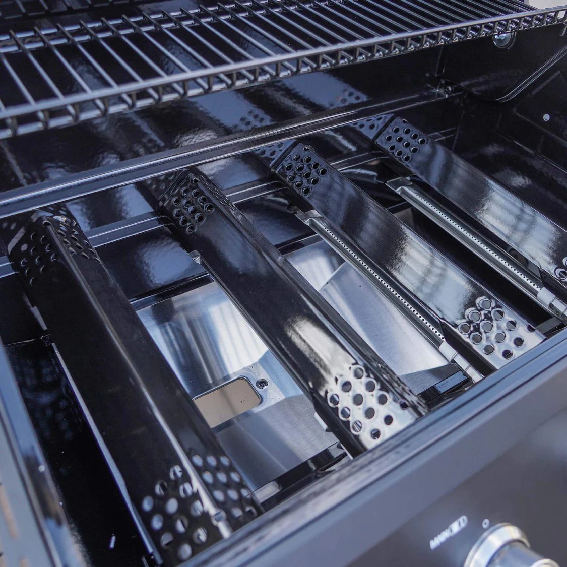 Close-up of a grill's interior with metal components and branding.