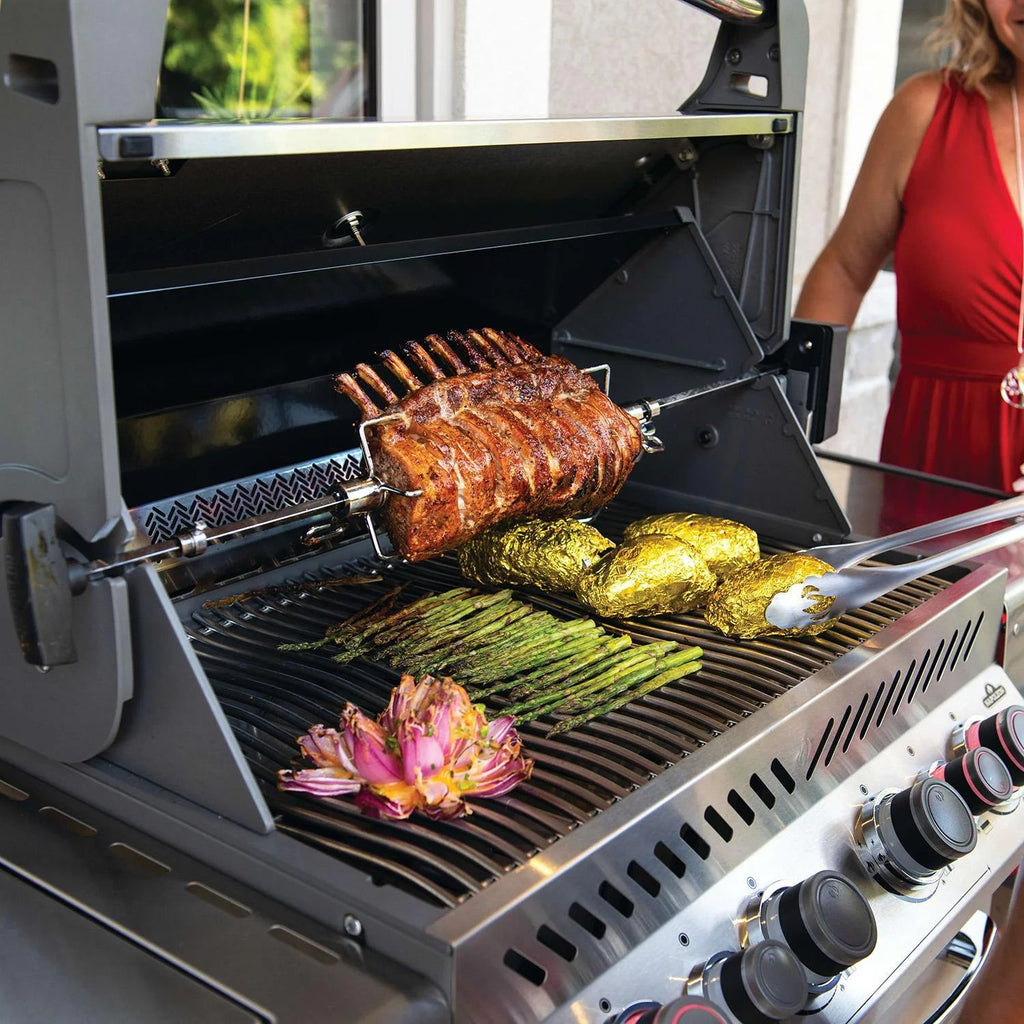 Grilled rack of ribs with asparagus, foil-wrapped potatoes, and artichoke on a BBQ grill